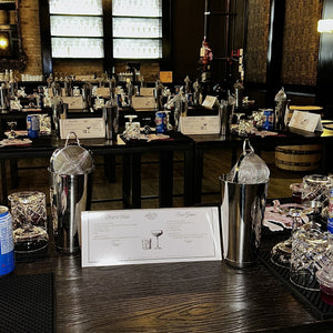 Bar setup with cocktail shakers, glasses, and a menu on a wooden surface.