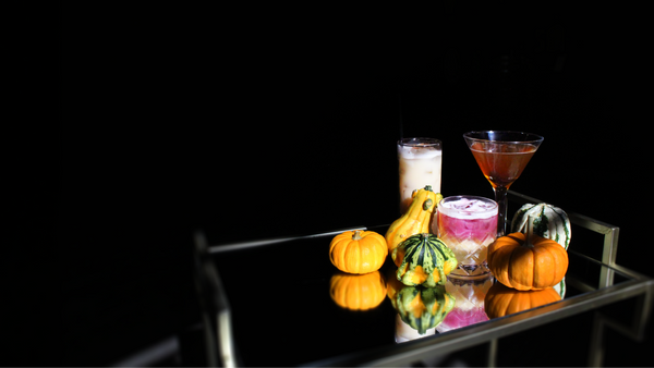 Tray with colorful cocktails and decorative pumpkins on a dark background