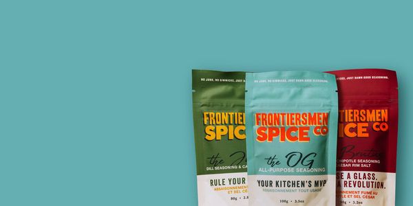 Three packages of Frontier Spice Co. on a teal background. The OG All Purpose Seasoning, The Brutus Chipotle Seasoning and Caesar rim salt, The Julius Dill Seasoning Caesar rim salt. Made local in Saskatoon Saskatchewan Canada.