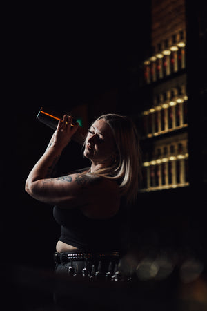 Bartender in black with preparing a drink craft cocktail with a metal shaker at Lucky Bastard Distillers headquarters, event room, bar and retail store where they sell craft vodka, gin and whisky in Saskatoon Saskatchewan Canada.