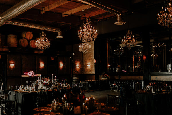 Dark moody red and black photo of Lucky Bastard Distillers with wooden floors and high ceilings, set up for an event with chairs and tables. 1920 style prohibition era Bar and event room decorated for a wedding in Saskatoon Saskatchewan YXE Canada must see must do while visiting bridge city.